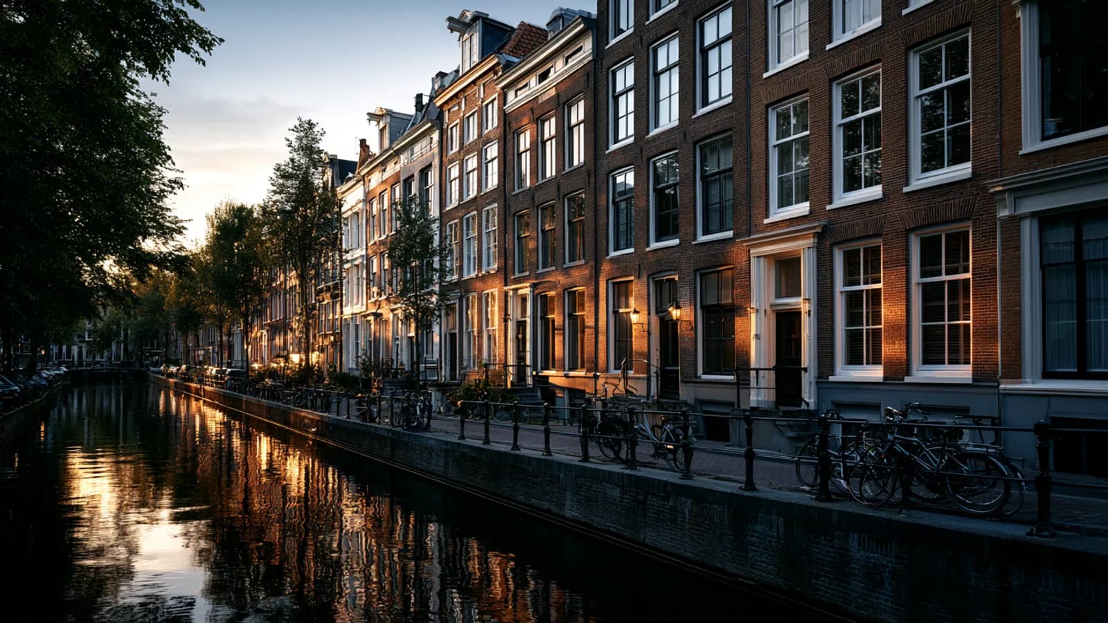 Typische Nederlandse grachtenpanden bij gouden uurlicht, fietsen langs het water